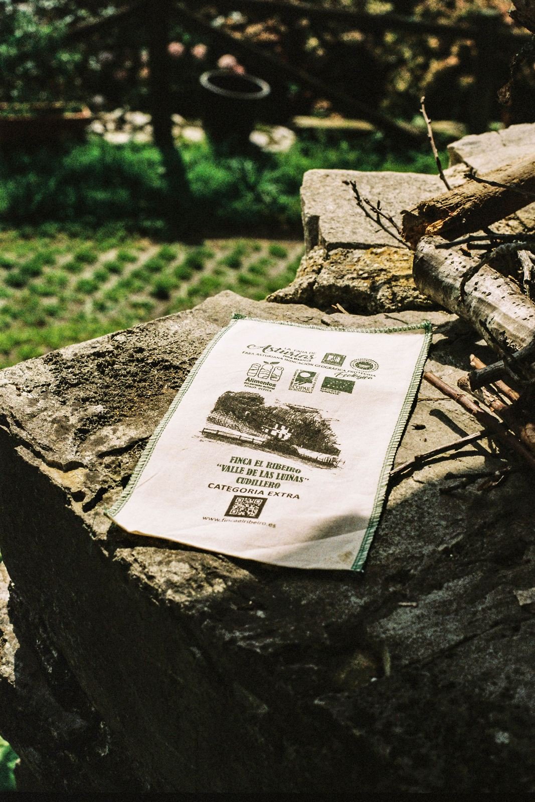 Finca el Ribeiro: saco de tela para faba asturiana con la ilustración de la finca, sobre un muro de piedra