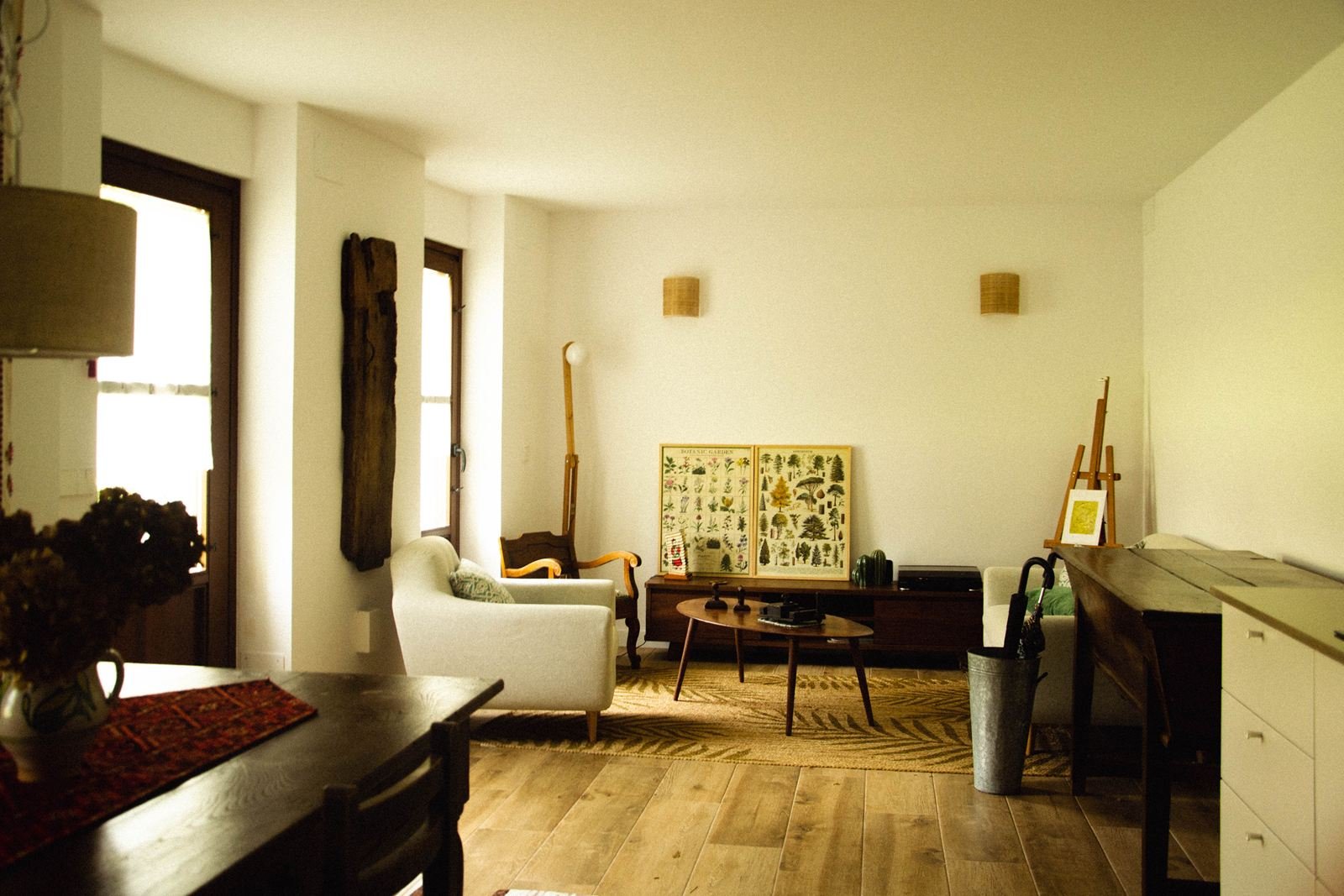 Reforma en San Cosme: salón reformado con sillón blanco, mesa baja de madera y suelo de tarima