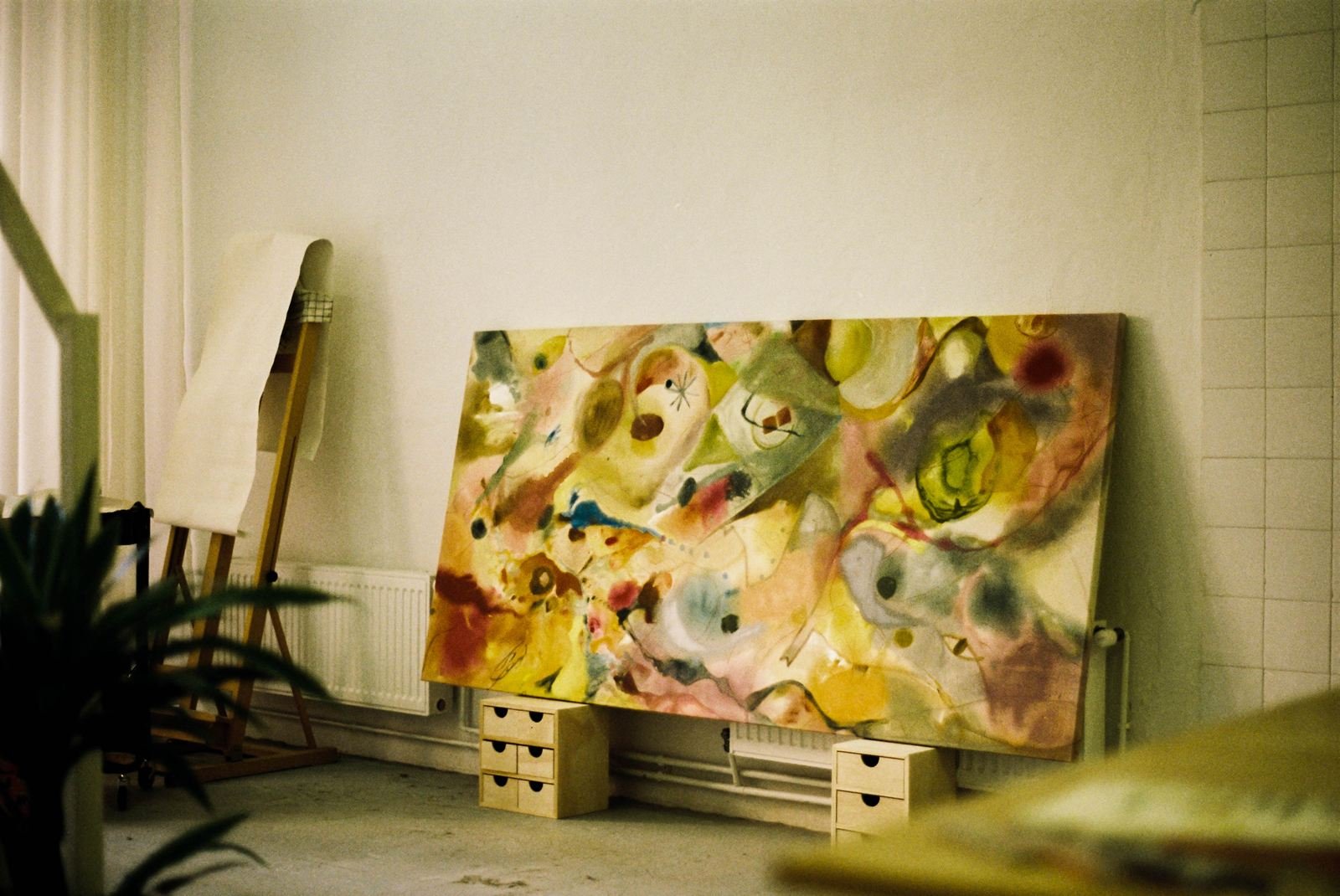 Estudio de Lucía Zamudio: gran lienzo abstracto en tonos amarillos apoyado en la pared sobre dos cajoneras